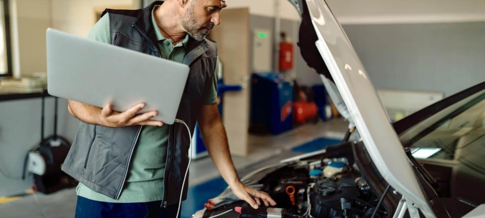 reparador-automoviles-usando-computadora-portatil-mientras-examina-motor-automovil-taller
